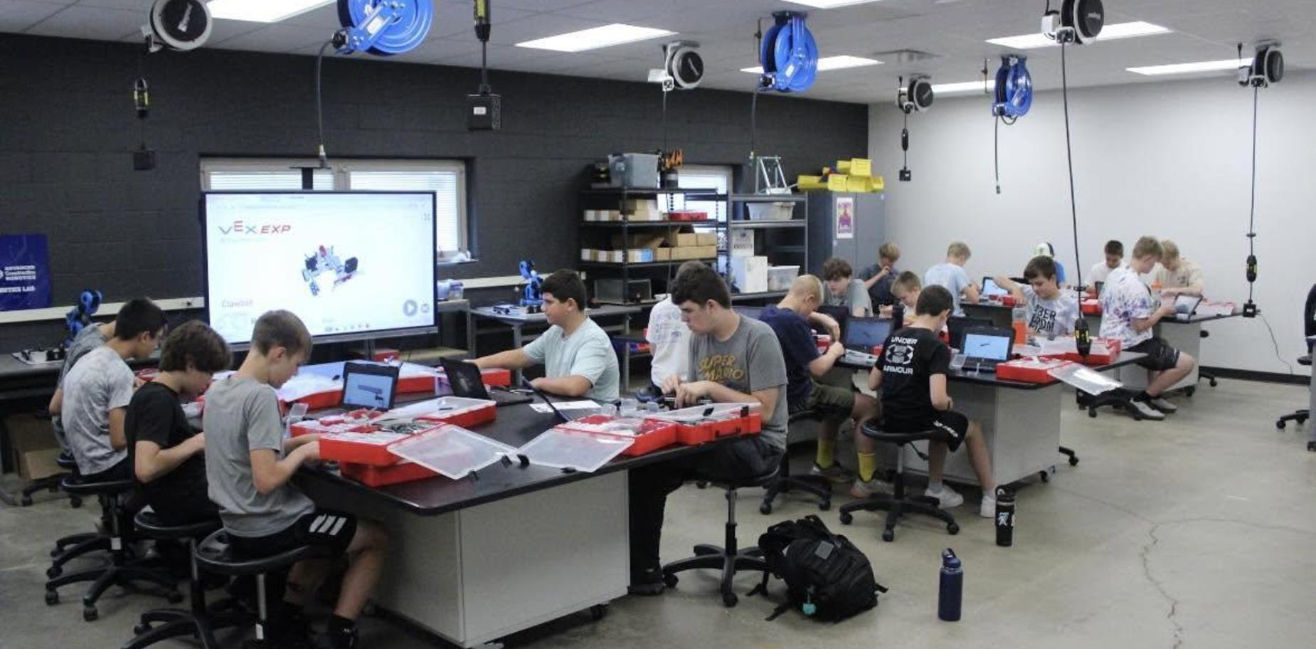 Students working on robotics kits in a classroom setting.