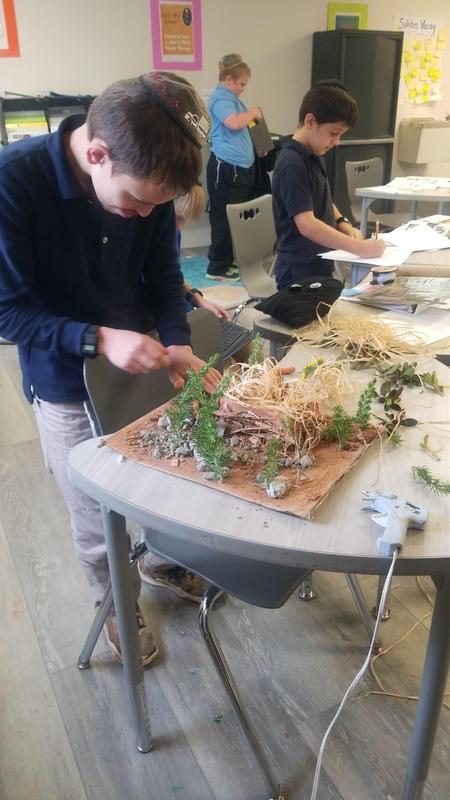 A student puts the finishing touches on his Native American Dwelling.