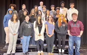 A group of high school students smiling on stage risers.
