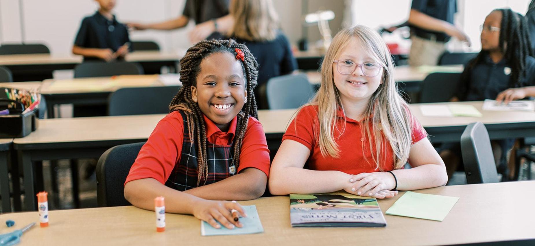 Two smiling students working together at a shared table