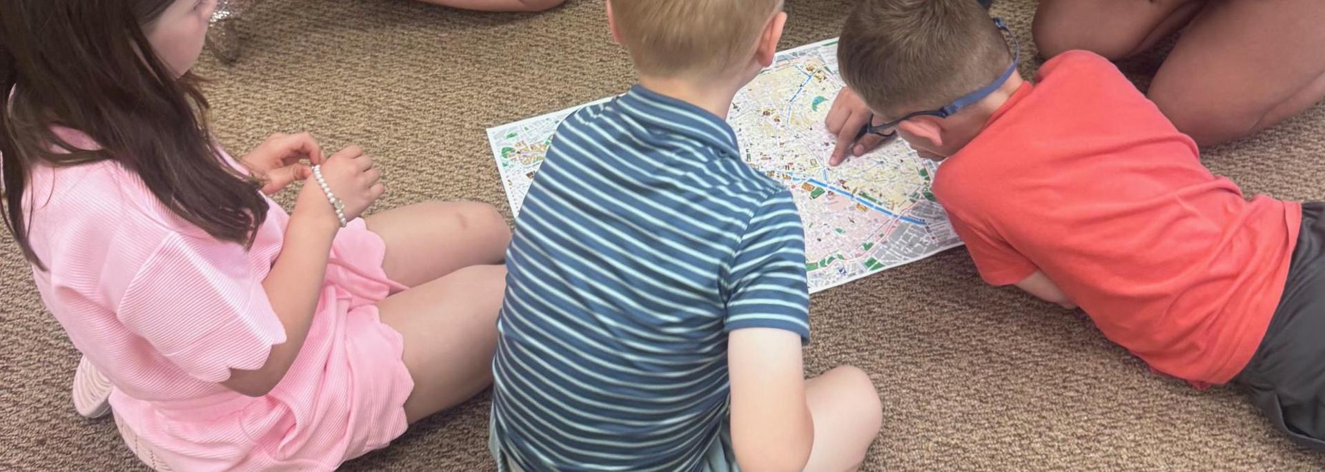 Children gathered around a map on the floor, engaged in a group activity.