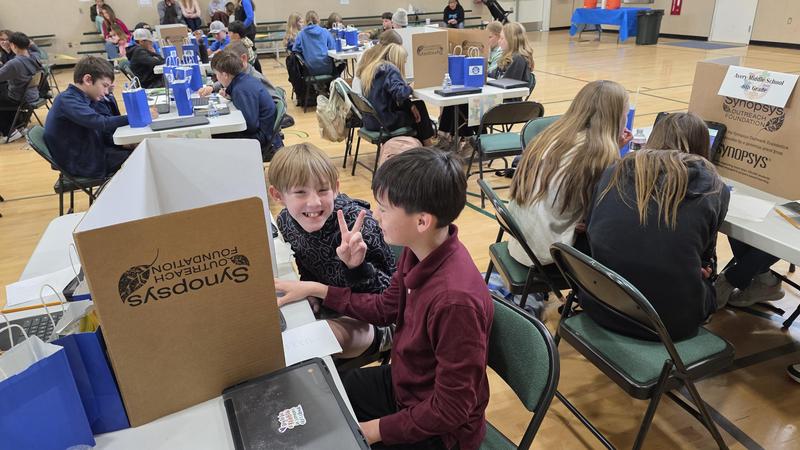 two young boys in a gym full of students
