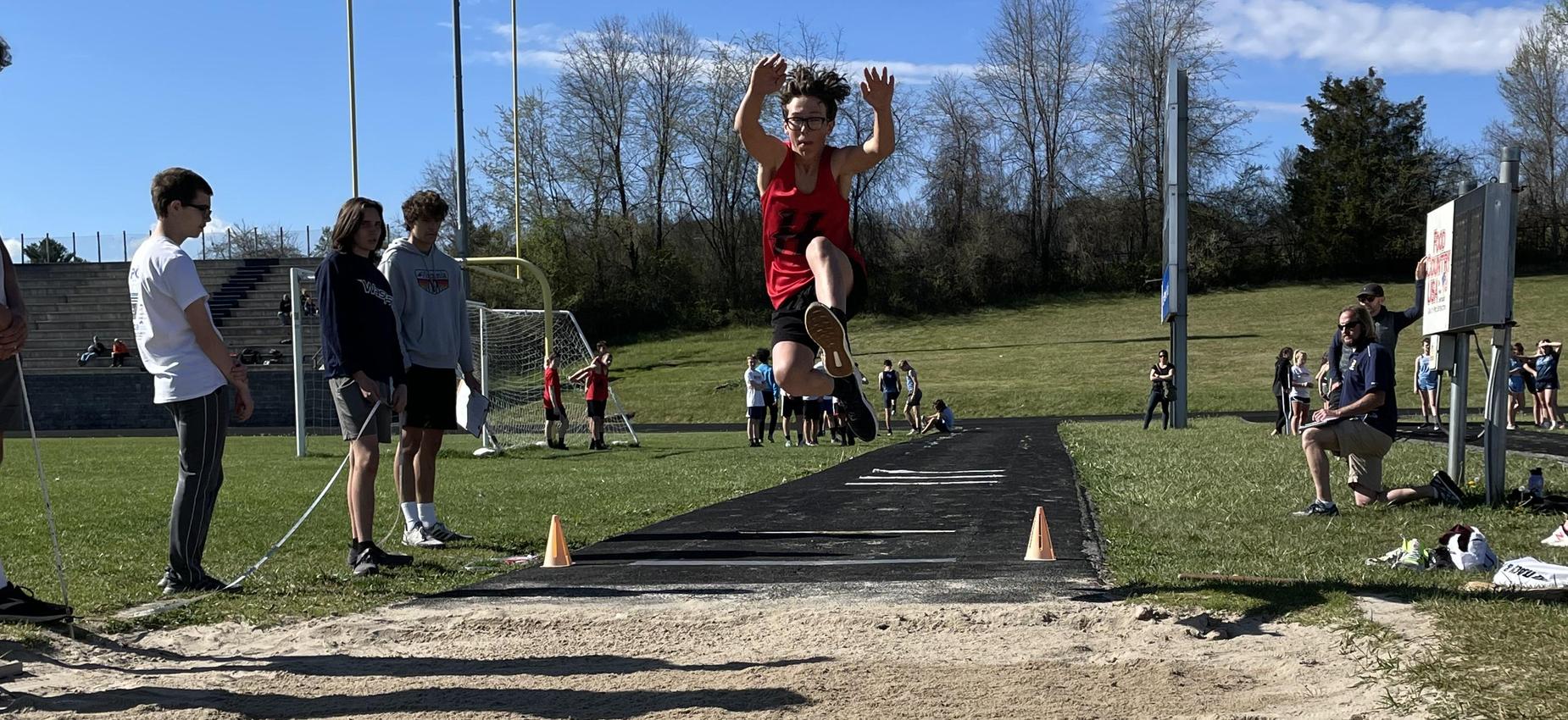 A boy long jumps into a sand pit.