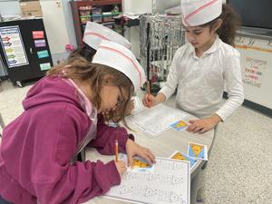 two girls working together at the math bakery.
