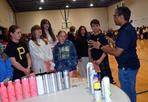 An educator discusses products with a group of students at a school event.