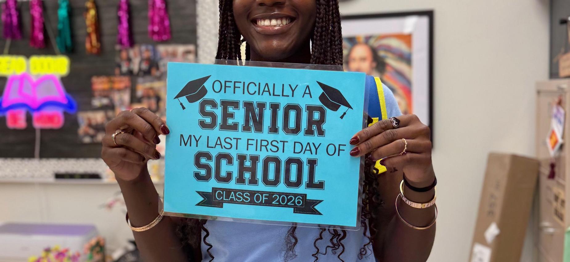 A students holding an "Officially a senior. My last day of school" sign
