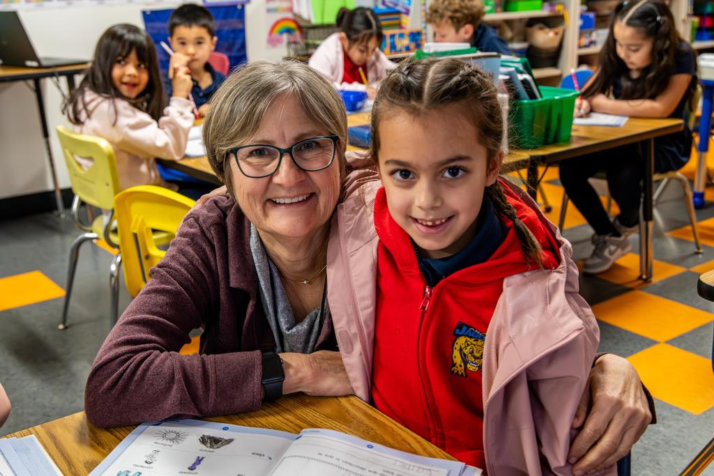 Arco Iris Teacher and Student smile for the camera while in a classroom