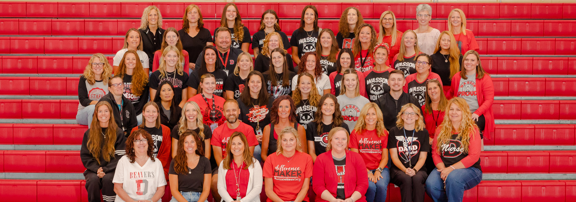 Wasson faculty and staff group photo wearing school colors in the gymnasium.
