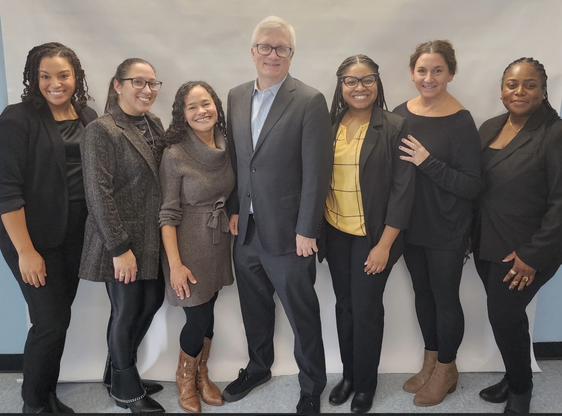 6 women standing with a man against a wall