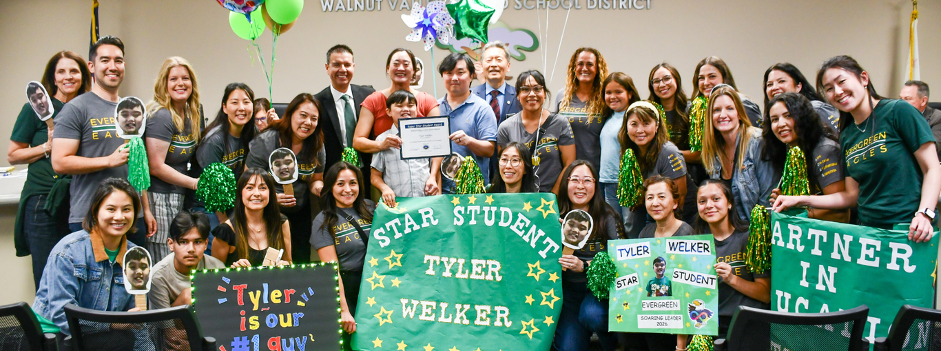 Celebration of a student with signs, balloons, and a group of supporters.