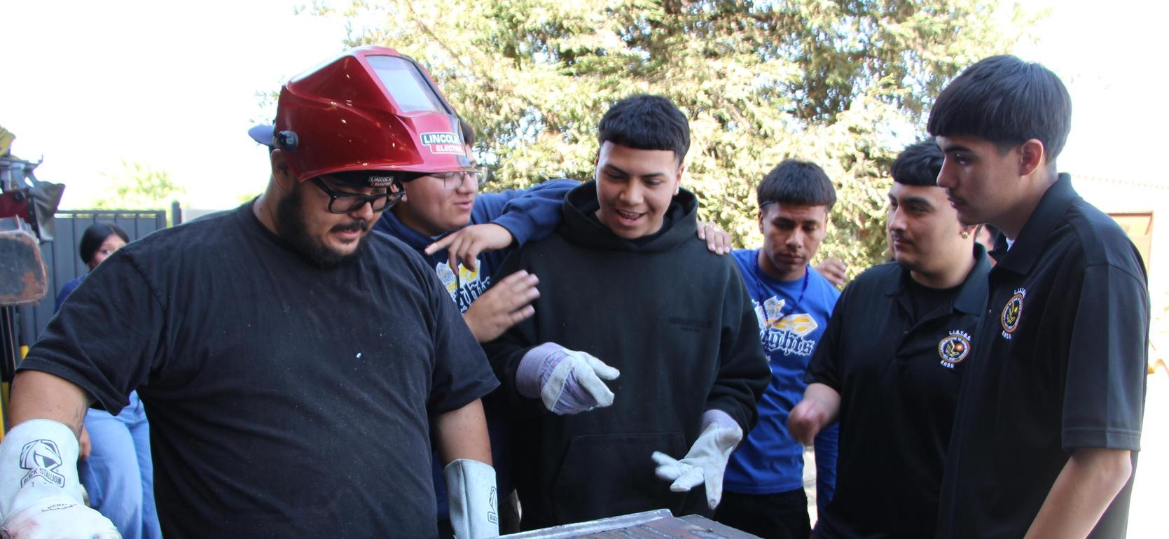 Group of young people gathered around a work table observing a project.