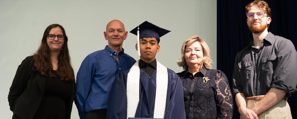 A graduate poses with family members in caps and gowns.