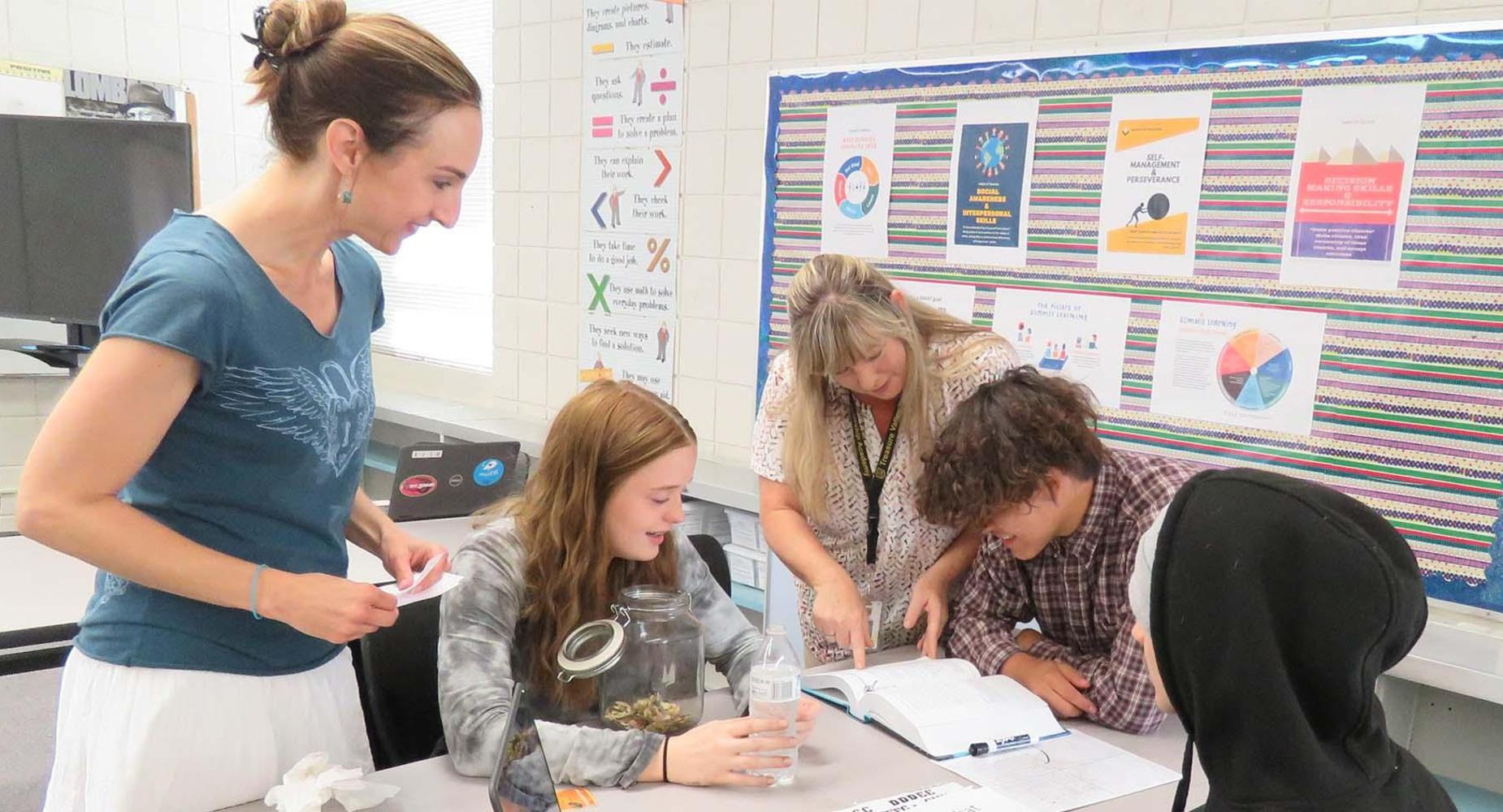 Group studies textbook at table in classroom