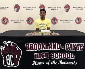 Aden Price seated at signing table
