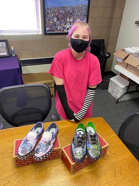 Student standing in front of shoes decorated with colorful drawings