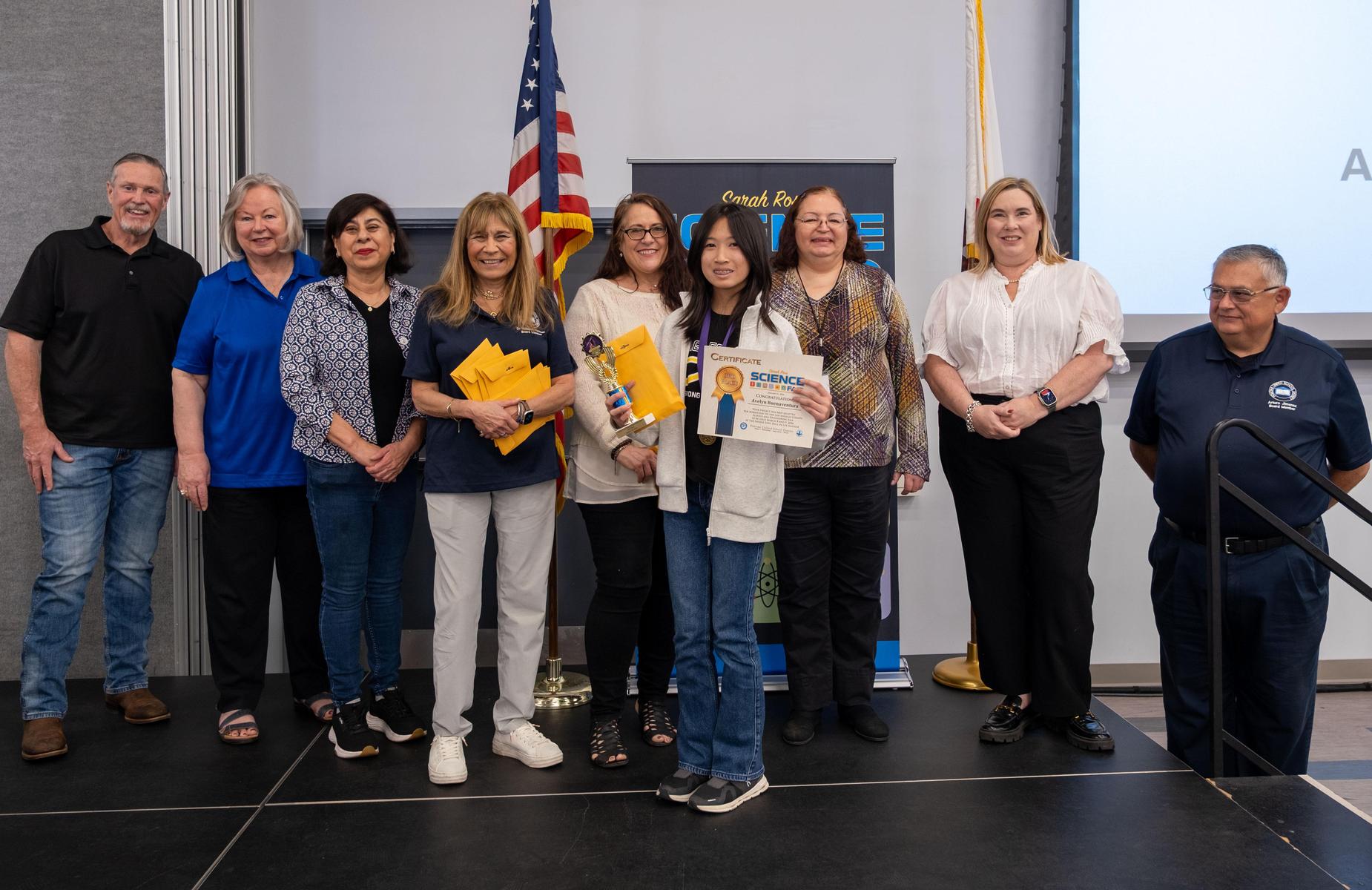 student with trophy and certificate with school board