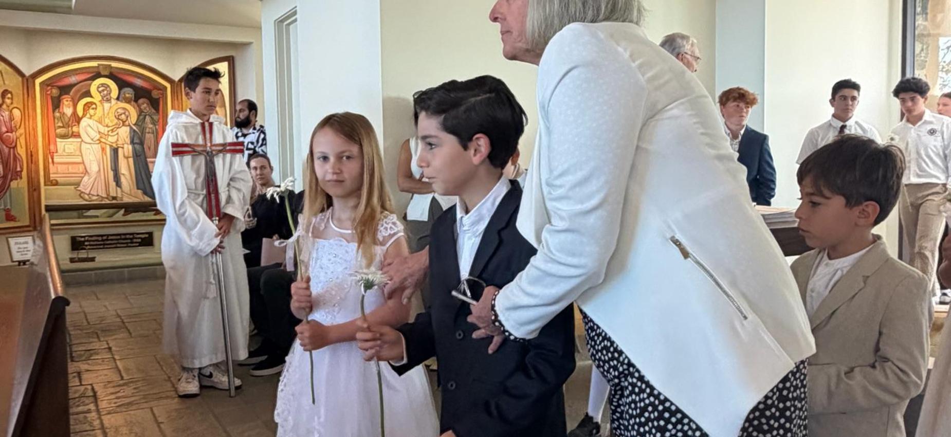 2nd grade students walk up aisle to crown Mary