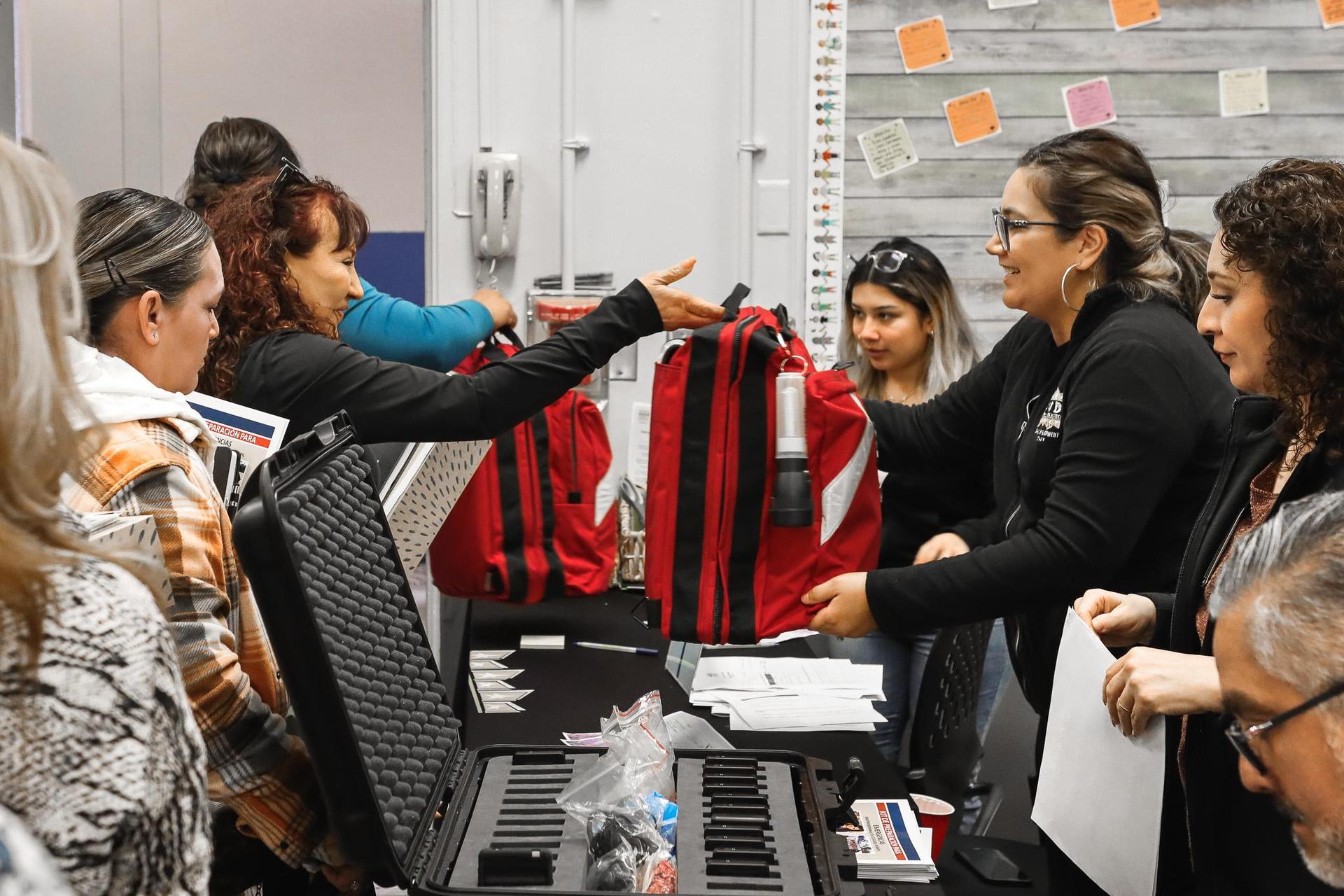 staff handing over emergency backpacks