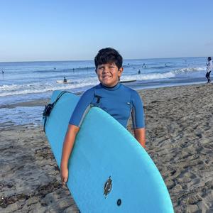 Boy in the sand with a surfboard