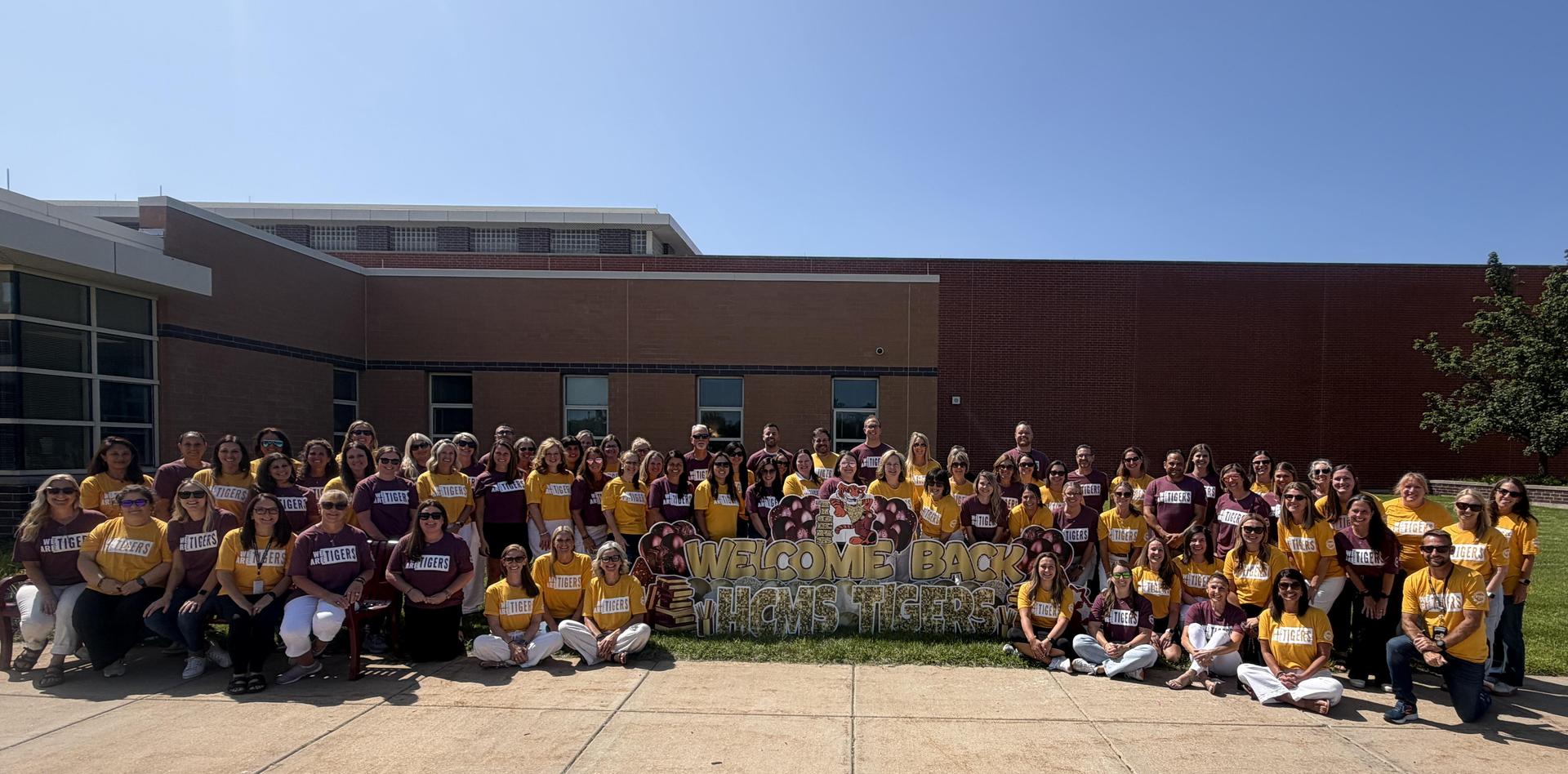 All staff smile outside of school building