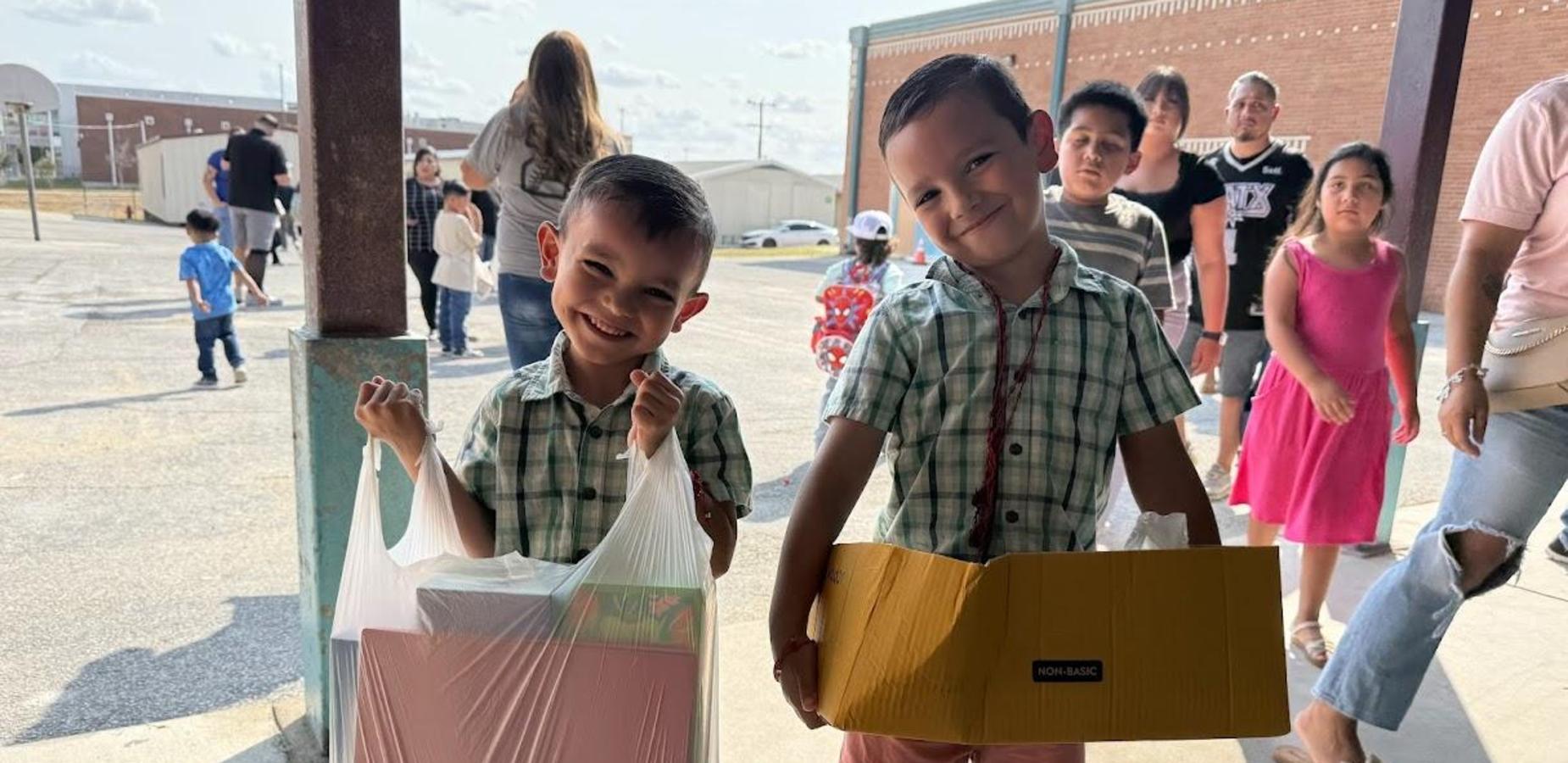 Two boys in plaid shirts holding school supplies