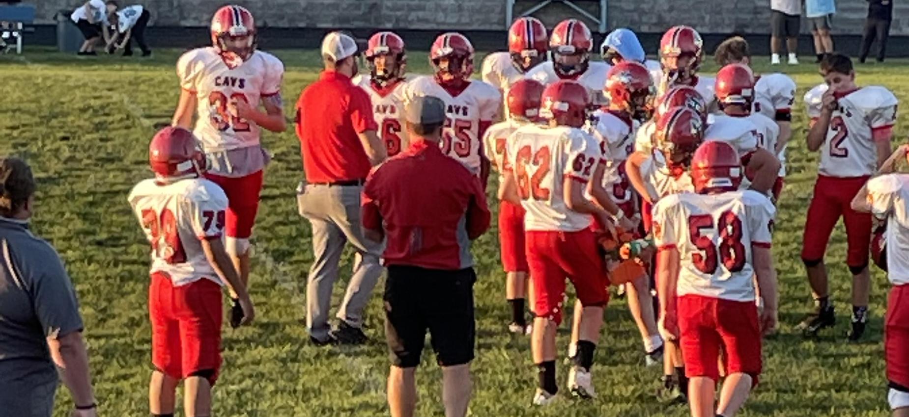 Football players stand on a field.