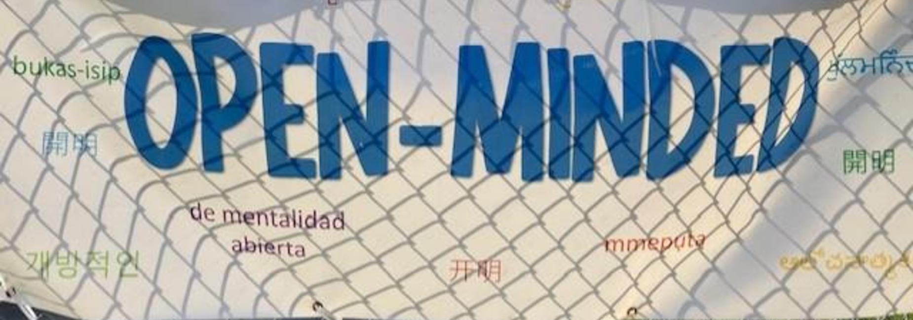 Colorful sign reading 'OPEN-MINDED' surrounded by various translations in different languages.