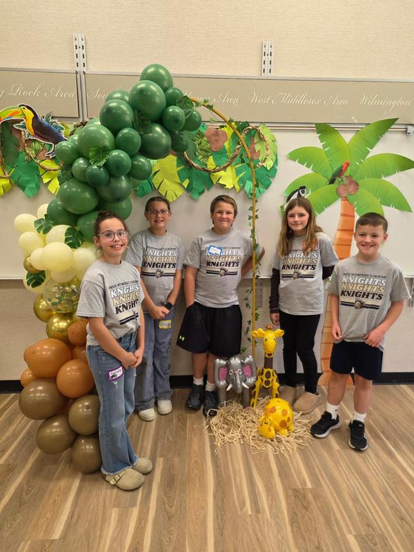 five students stand in front of jungle set up