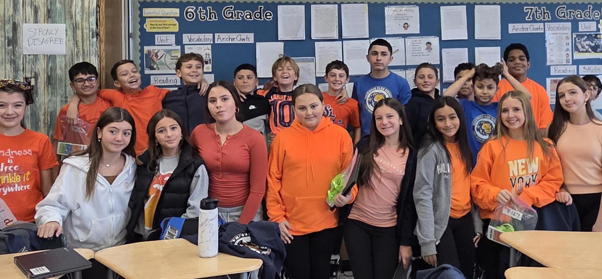 A diverse group of students poses together in a classroom, smiling and wearing colorful outfits.