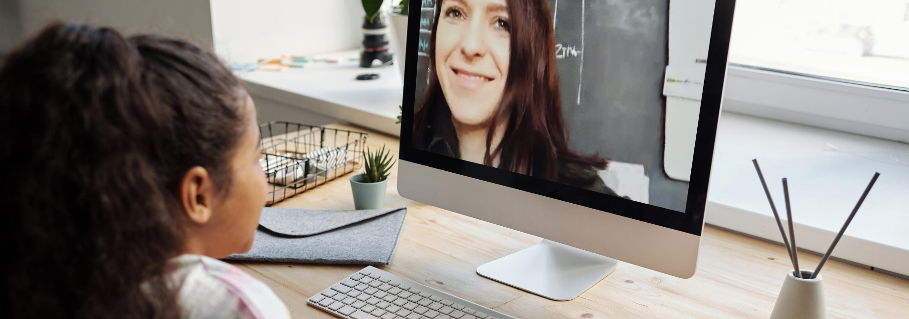 girl smiling at woman on computer monitor