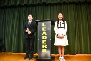 Fifth-grade students Queena Chen and Fares Beltram pose beside the “Leaders” podium.