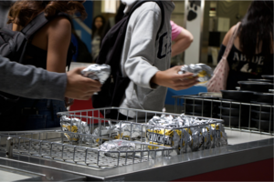Teenagers grab chicken sandwiches wrapped in foil.