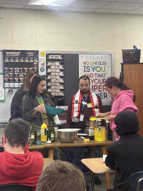 Students collaborate to prepare ingredients for hummus in a classroom setting.