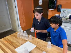 Two boys work together to build a cup tower