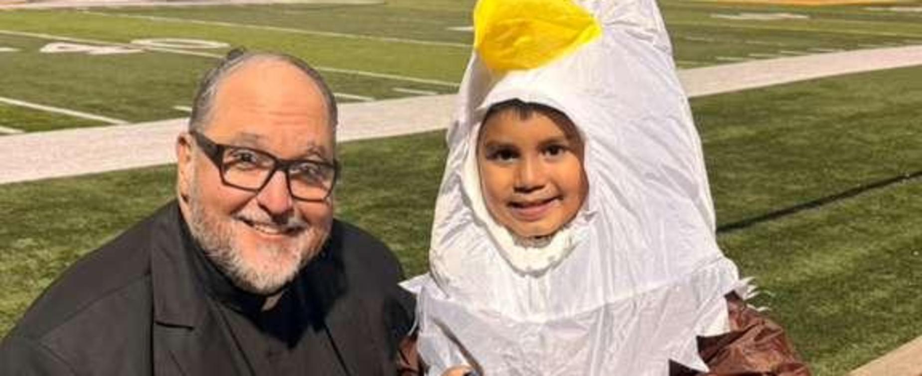 A man and a child dressed in costumes, smiling together at a sporting event.