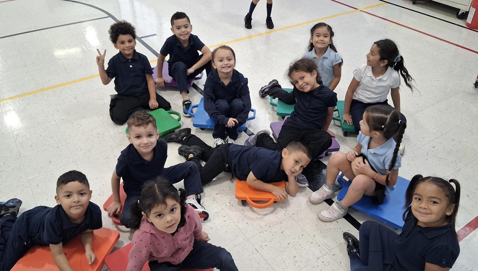 A group of children sitting on colorful mats, smiling and posing for the camera.