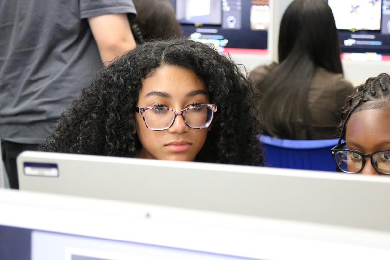 An African American teen with curly hair and curly hair looks at a computer