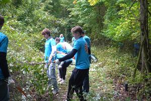 A student pulls on some debris cut from the brush.