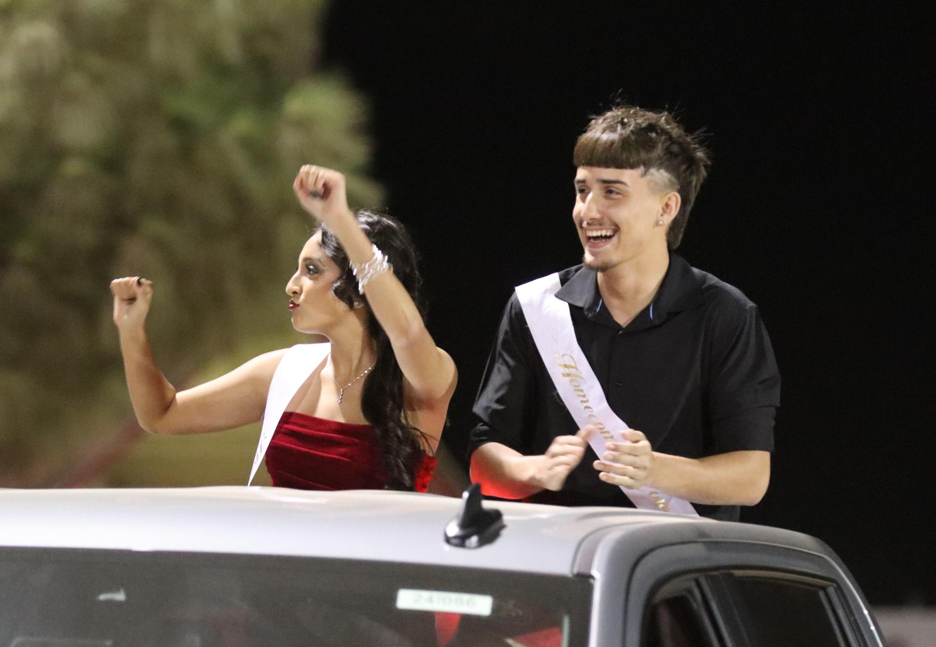 homecoming king and queen candidates entering the stadium in trucks