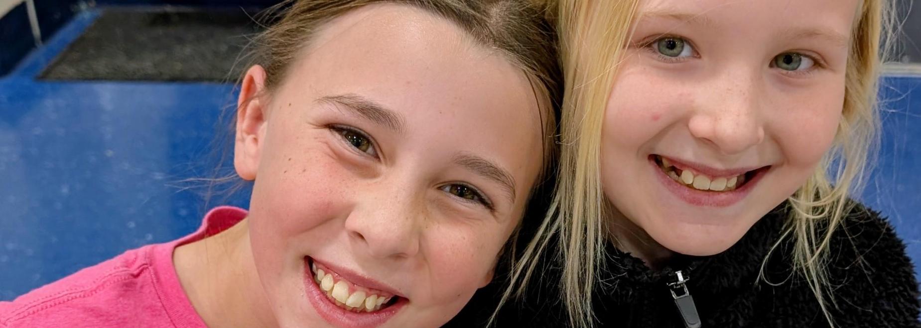 Two girls smiling with one holding a sandwich, showcasing friendship and joy.