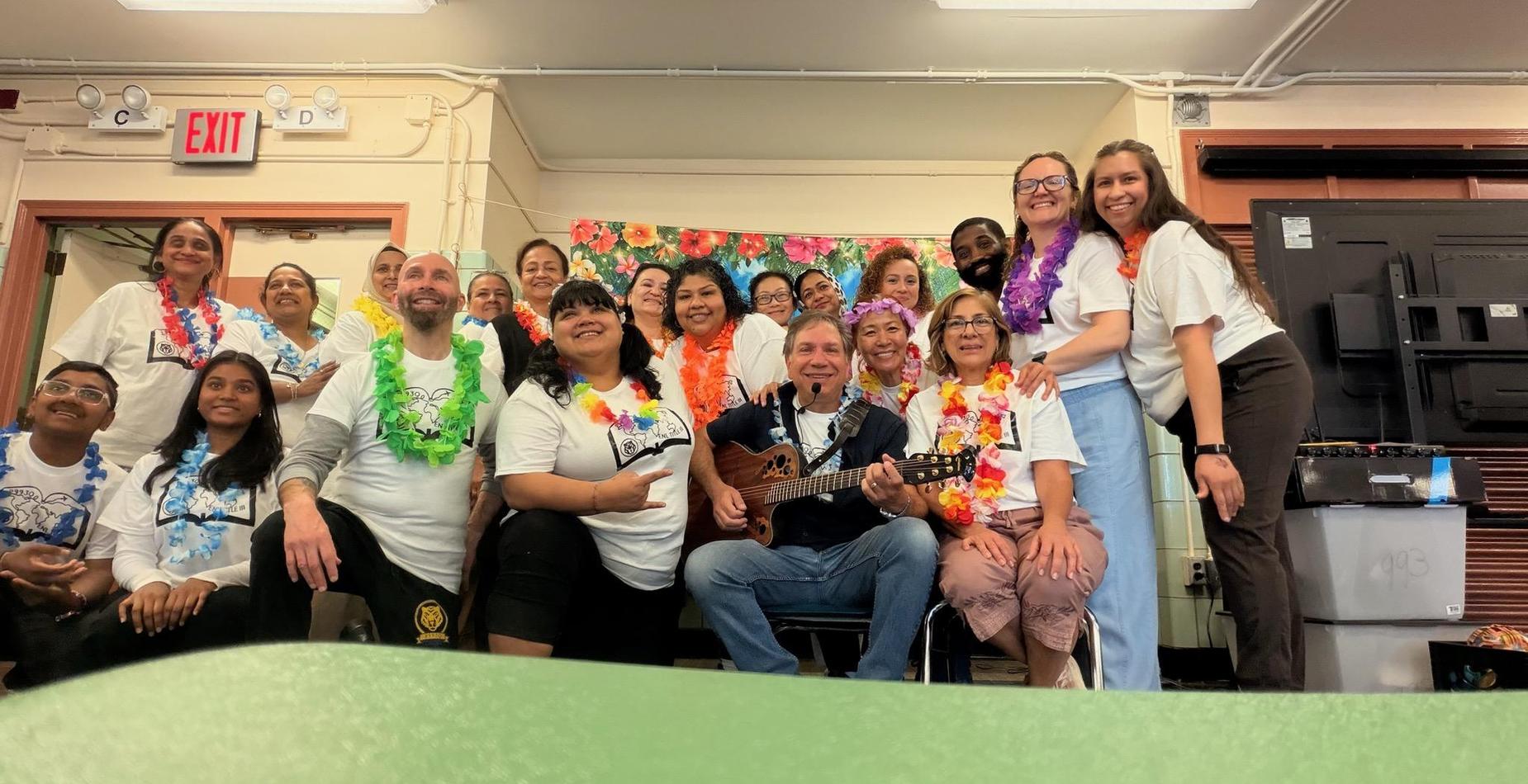 Large group of people in Hawaiian shirts posing with a guitar.