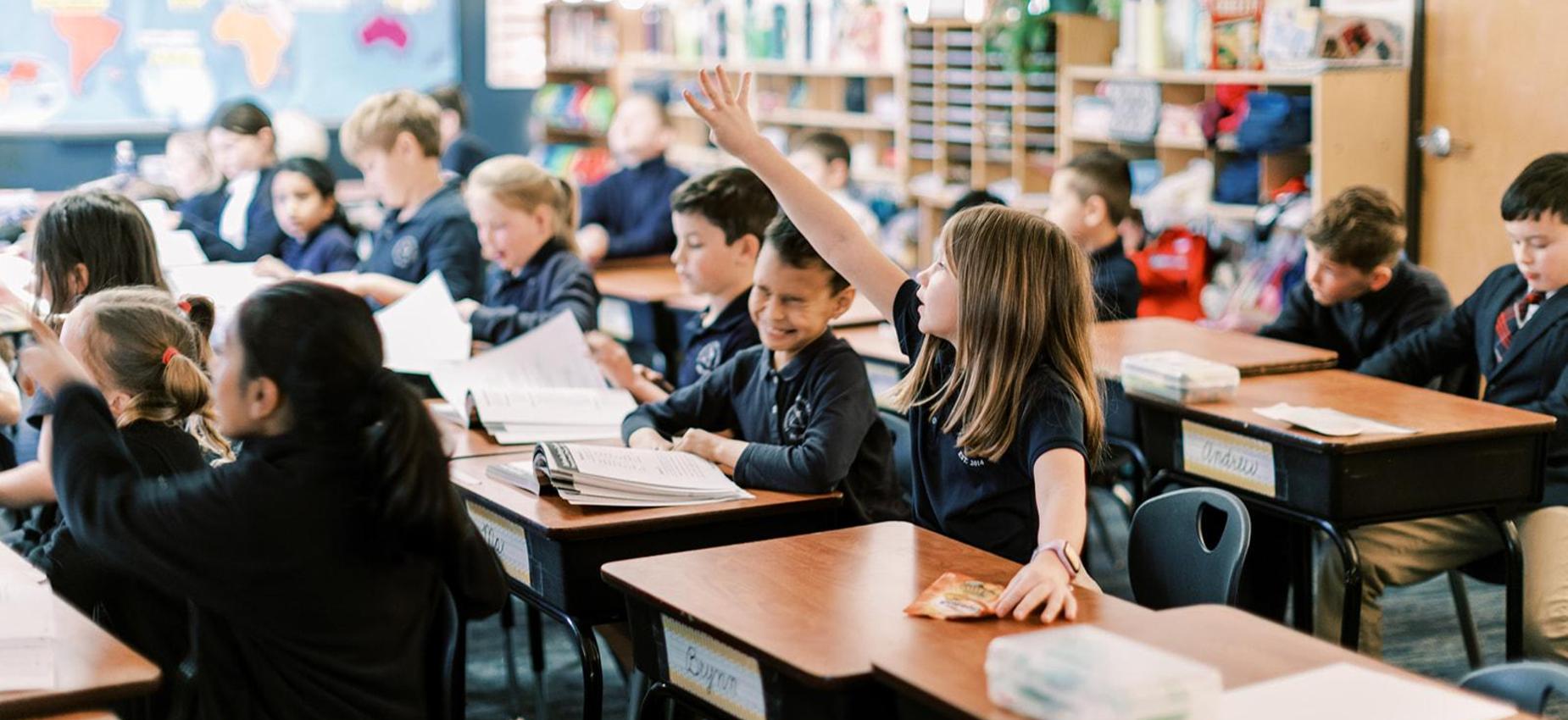Elementary student raises her hand to answer a question in class