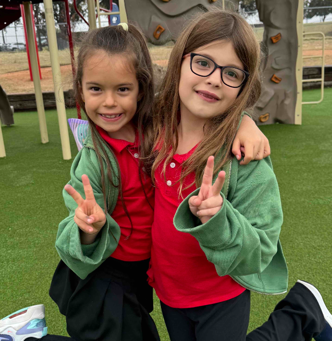 Young students hug and hold up their fingers in a peace sign