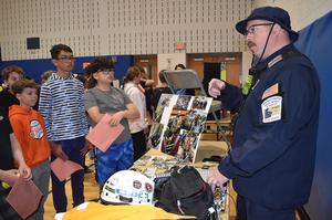 Man in uniform speaking to children about safety and equipment.