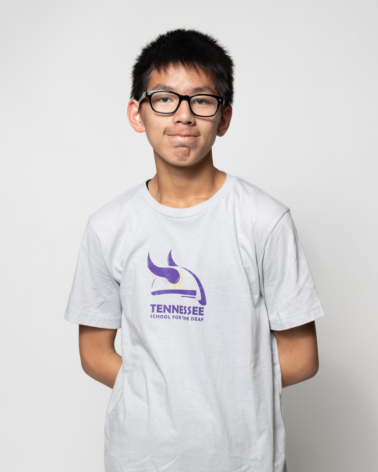 Boy wearing a white t-shirt with a logo for Tennessee School for the Deaf.