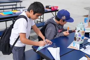 two boys coloring college pennants