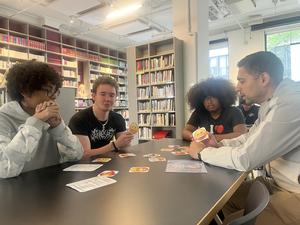 Three participants discussing song emojis with a facilitator at a table.