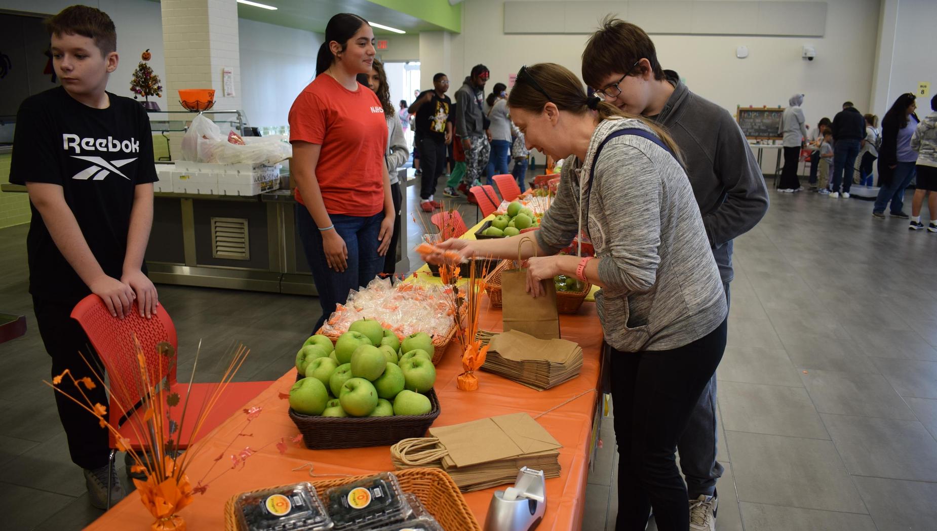 People at a community event with a food table and green apples.