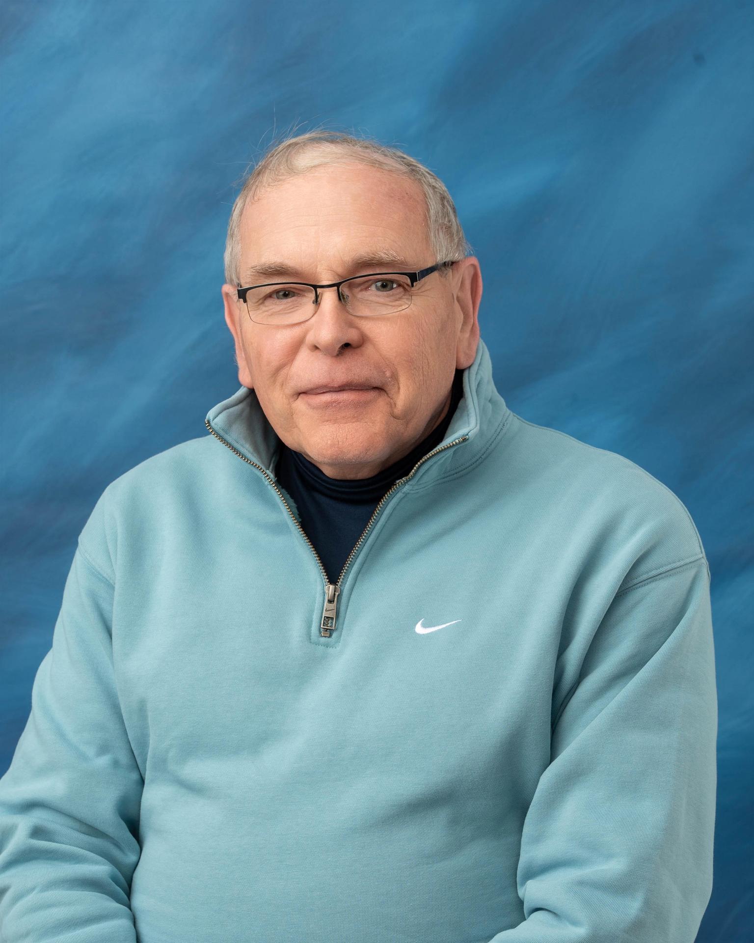 Photo of Mr. Jerry Brant with a light blue shirt in front of a blue background.