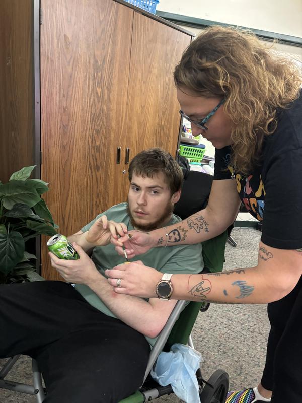 A woman helps a young man with a beverage while he looks intently at her.